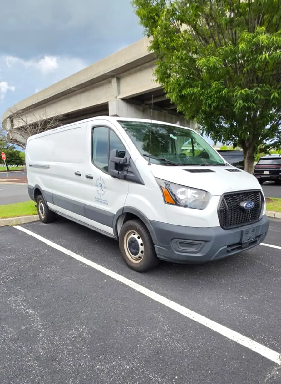 Rush 24/7 white cargo van parked, front angle view showing the company logo on the cab door
