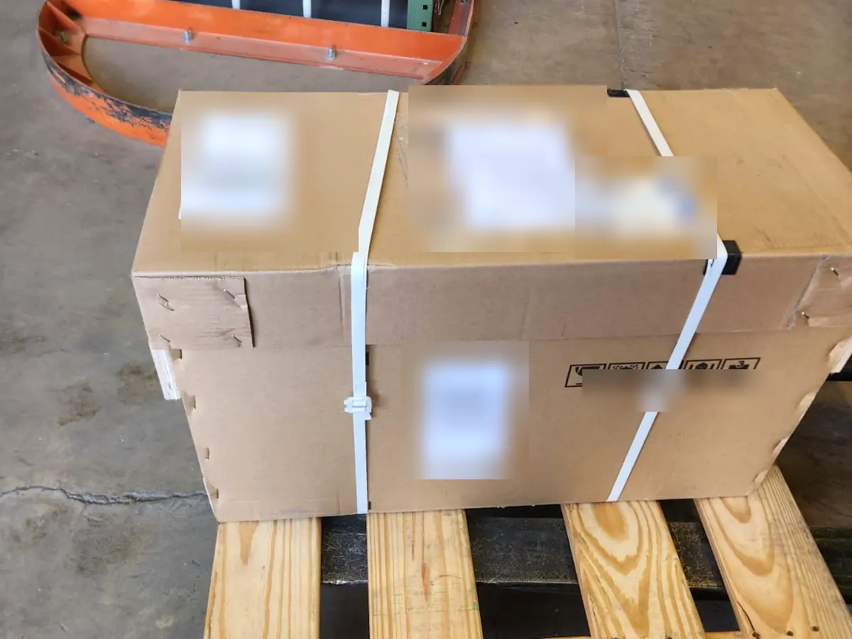 A strapped, palletized shipment staged on the Rush 24/7 warehouse floor, ready for air freight, with shipping labels blurred